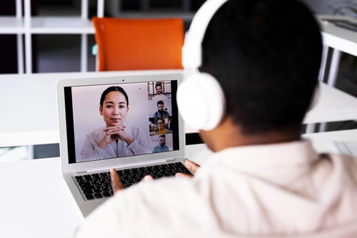 Cuffie smart working: ragazzo con cuffie di spalle e schermo computer con videochiamata